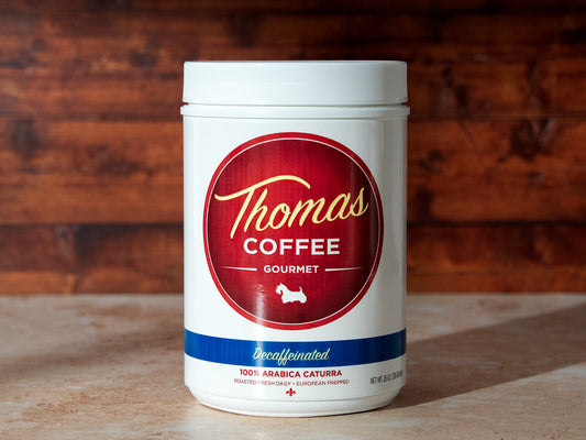 Thomas Coffee Gourmet decaffeinated container on a wooden surface with a wooden background