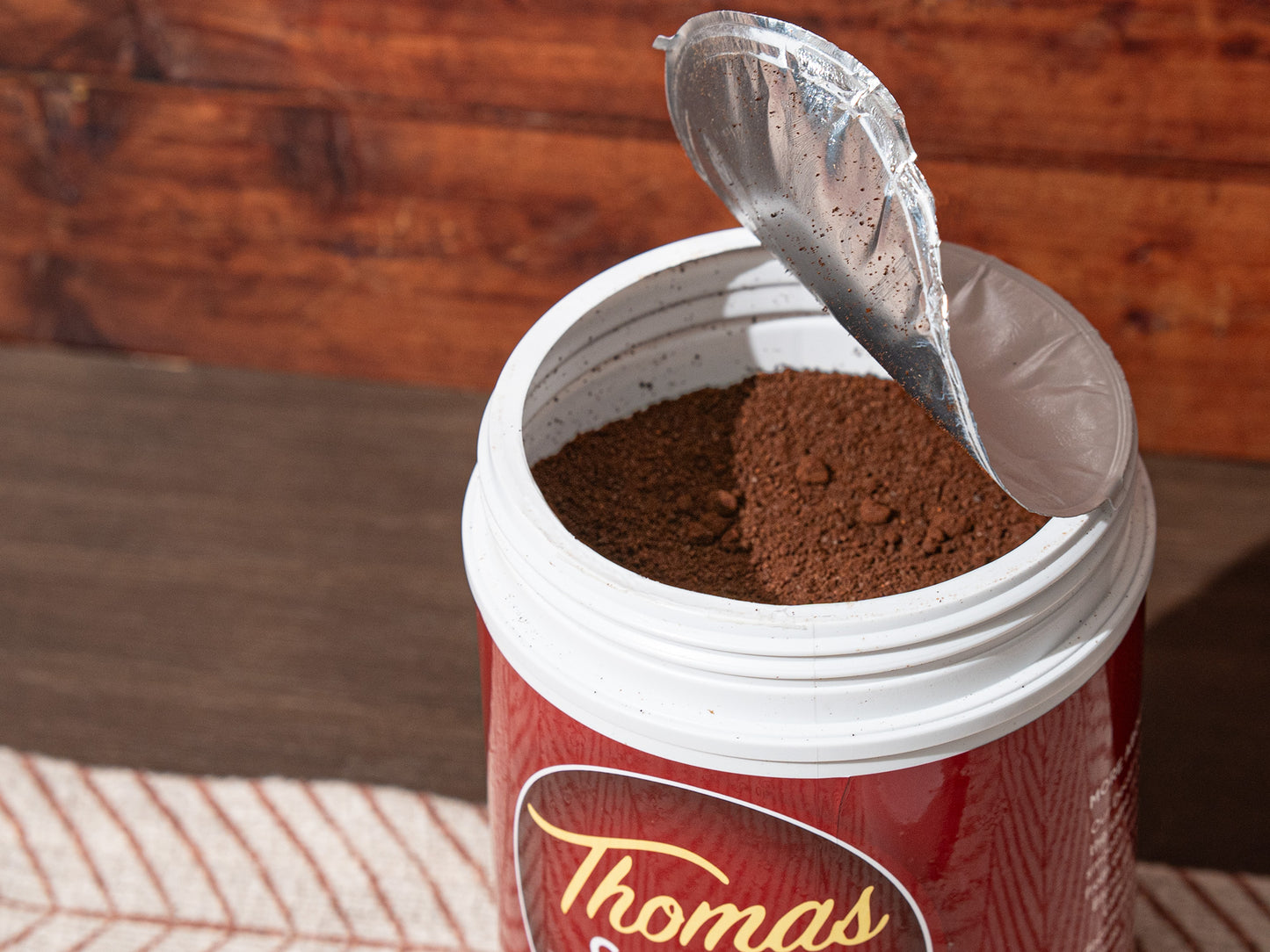 Opened Thomas Coffee container with red label on a wooden background