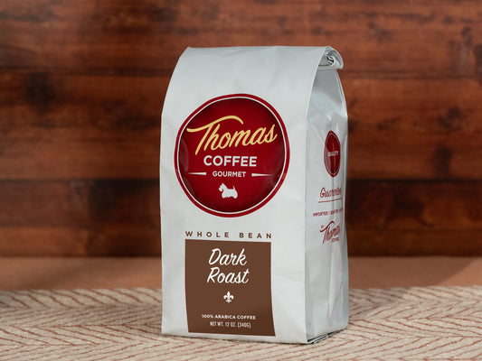 Thomas Coffee Gourmet whole bean dark roast coffee bag on a wooden surface
