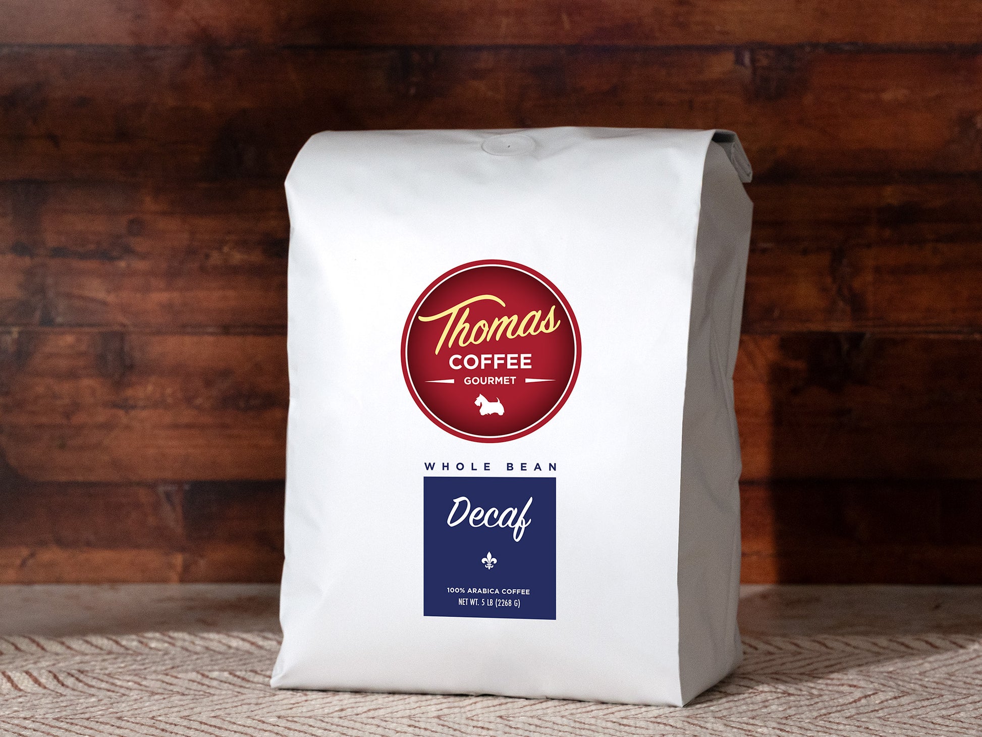 White coffee bag with Thomas Coffee Gourmet Decaf label on a wooden background