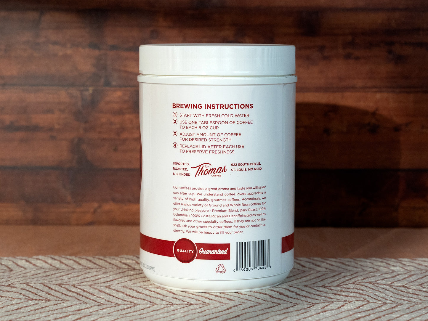 Thomas Coffee white coffee container with red text and branding on a wooden surface